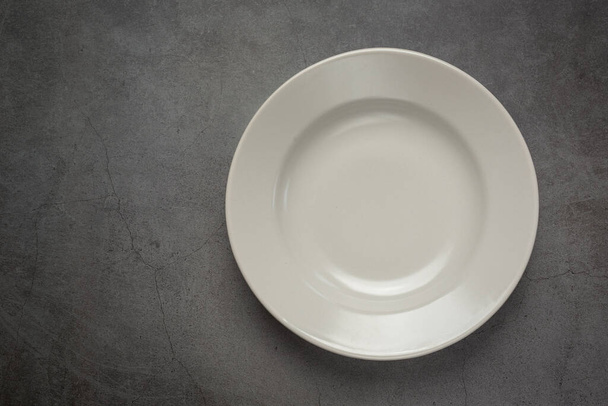 белая круглая пустая тарелка на темном фоне - Фото, изображение