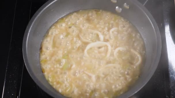 Close-up shot of bubbling boiling ingredients while cooking seafood risotto. Boiling frying pan surface in slow motion. White smoke rising up on dark background. Restaurant. Full hd - Footage, Video