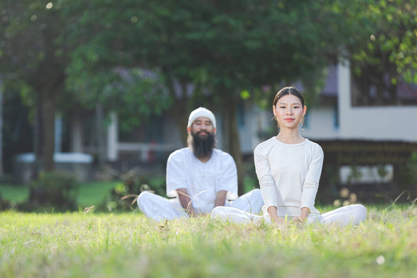 two people in white outfit doing yoga in nature - Foto, Bild