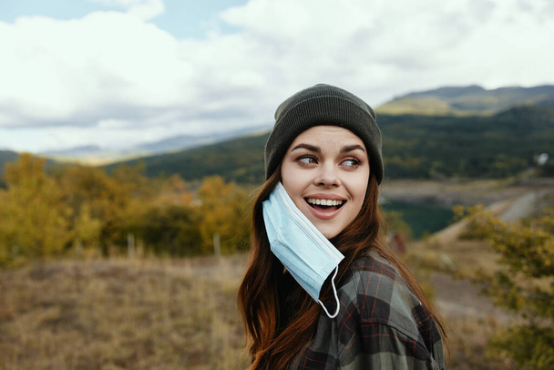 Energetic woman with a medical mask for a walk in nature in the autumn forest - Photo, Image