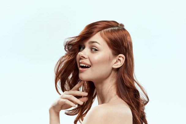 Csinos nő gazdaság haj mosoly kozmetikumok életmód meztelen vállak frizura ellátás báj fény háttér - Fotó, kép
