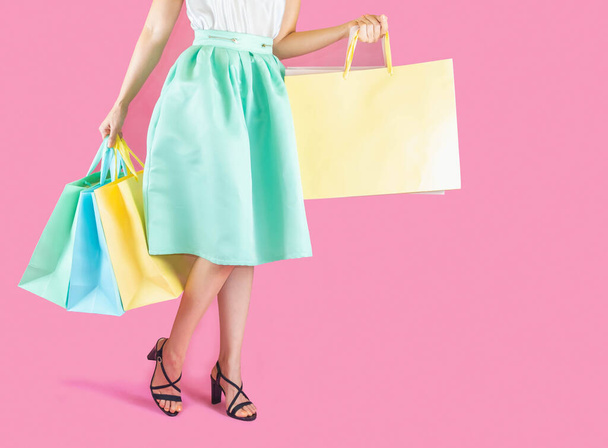 Low Section Of Woman Holding Shopping Bag Against Pink Background - Valokuva, kuva