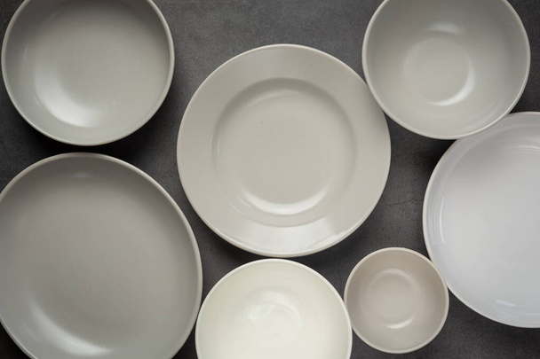 λευκά στρογγυλά άδεια πιάτα και κύπελλα σε σκούρο φόντο - Φωτογραφία, εικόνα