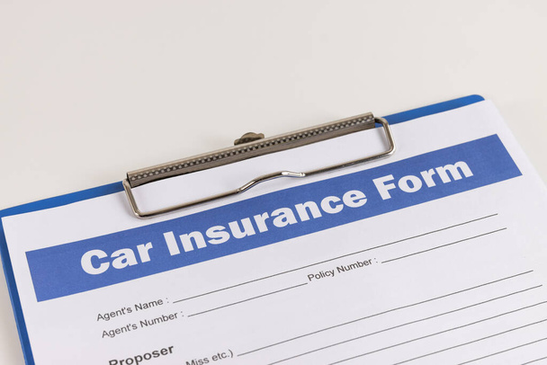 Formulario de reclamación de seguro de automóvil o documento de seguro de automóvil en la inclinación izquierda y portapapeles en la mesa de la oficina blanca - Foto, Imagen