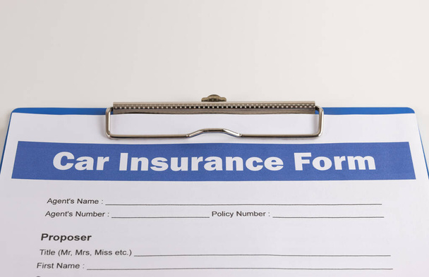 Formulario de reclamación de seguro de automóvil o documento de seguro de automóvil y portapapeles en la mesa de la oficina blanca - Foto, Imagen