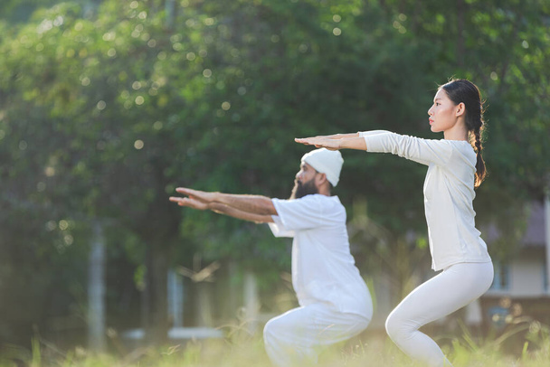 dos personas en traje blanco haciendo yoga en la naturaleza - Foto, imagen