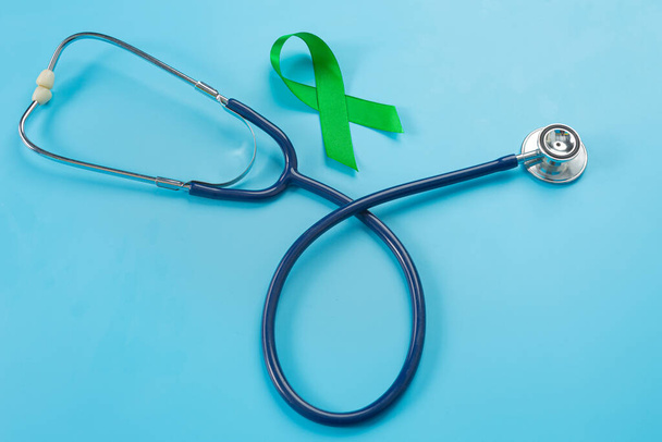 Mentális egészség világnapja; zöld szalag és sztetoszkóp kék alapon - Fotó, kép
