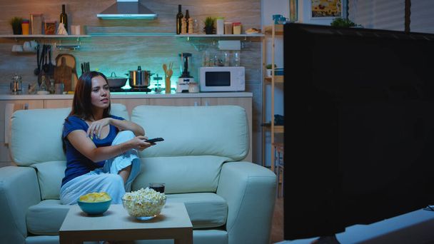 Женщина смотрит телевизор, собирая стакан сока - Фото, изображение