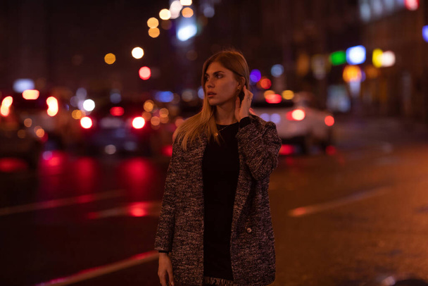 Young fashion woman walking on city street at night. - 写真・画像