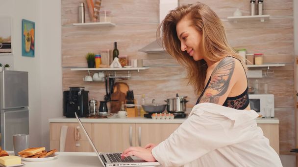 Attractive housewife typing on laptop - Fotó, kép