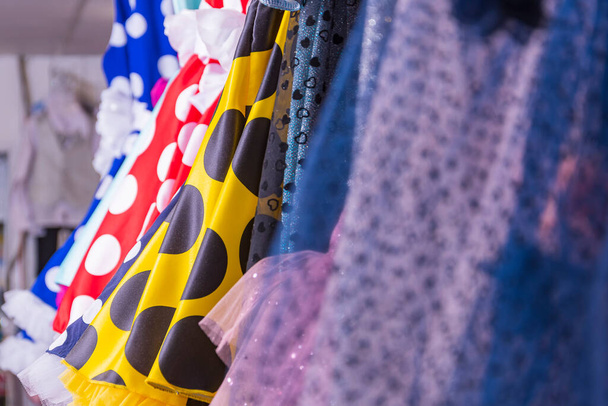 Una colección de brillantes vestidos de verano para niños en el escaparate. Tienda con una gran selección de ropa. - Foto, Imagen