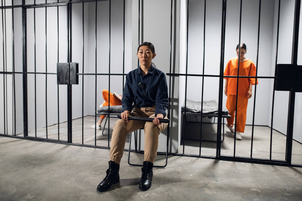 A young asian woman in uniform guards two criminals in prison - Fotó, kép