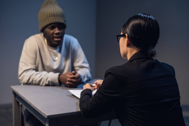 Ένας μαύρος ακούει τα δικαιώματά του από έναν πολιτικό δικηγόρο σε ένα τραπέζι σε ένα επισκεπτήριο σε μια κρατική φυλακή. - Φωτογραφία, εικόνα
