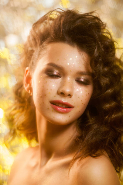Creative winter makeup with golden snowflakes on her face and wavy hairstyle - 写真・画像
