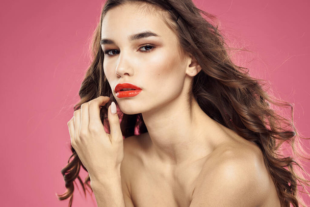 Houkutteleva nainen muodikas kampauksen paljasti olkapäät ja punaiset huulet vaaleanpunainen tausta - Valokuva, kuva