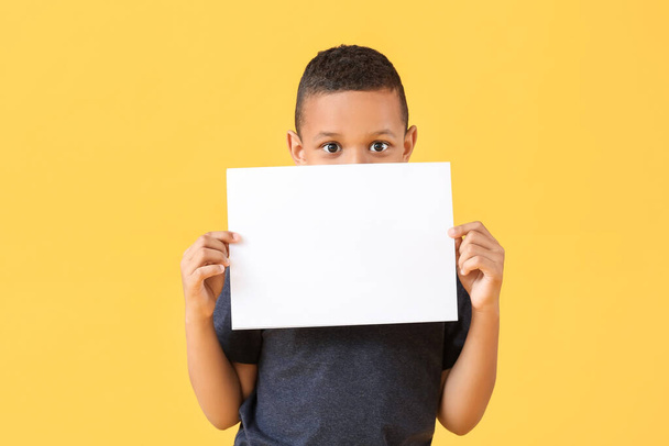 Little African-American boy with blank paper sheet on color background - Foto, Bild
