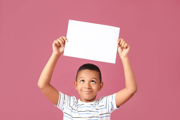Kleiner afroamerikanischer Junge mit leerem Papierbogen auf farbigem Hintergrund - Foto, Bild