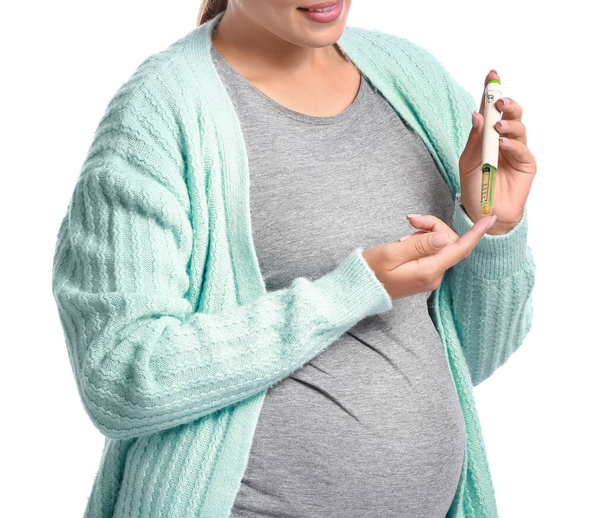 Pregnant diabetic woman with lancet pen on white background - 写真・画像