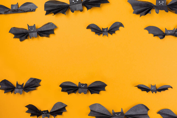 Bats made of paper are arranged on an orange background. Copy space. Flat lay. The concept of Halloween, and holiday decorations. - Fotografie, Obrázek