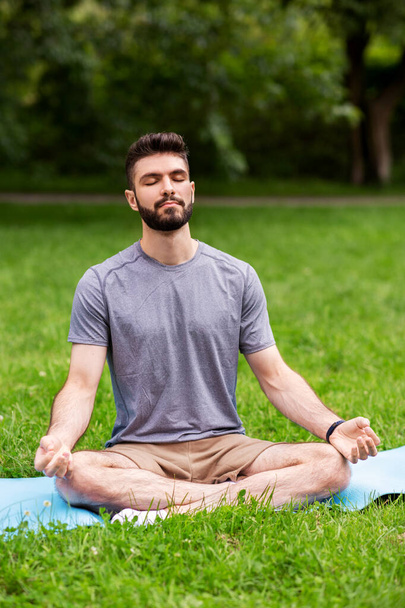 young man meditating at summer park - Фото, изображение