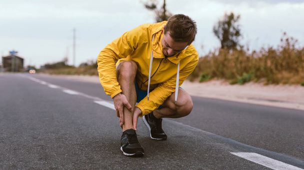 Runner man with shin trauma and pain on the road - Фото, зображення