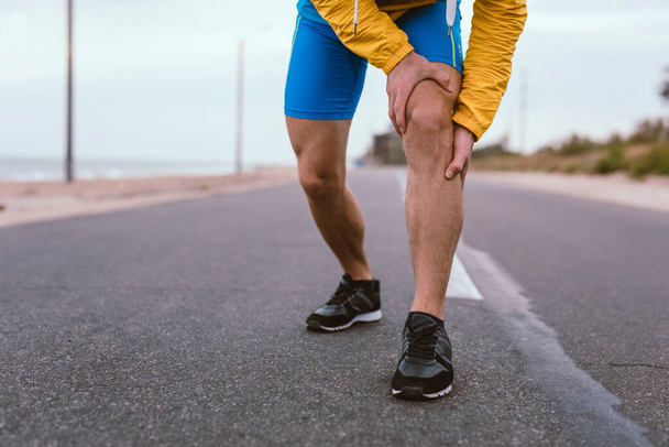 Runner man with knee injury and pain on the road - Foto, imagen