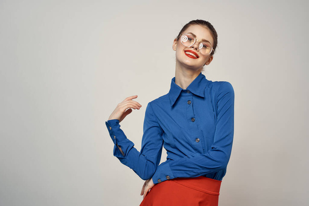 γυναικείο μοντέλο σε μπλε πουκάμισο και κόκκινα γυαλιά φούστα όμορφο στούντιο μακιγιάζ πρόσωπο - Φωτογραφία, εικόνα