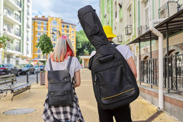 Trendy teenage hipsters boy and girl walking talking on city street - Fotó, kép