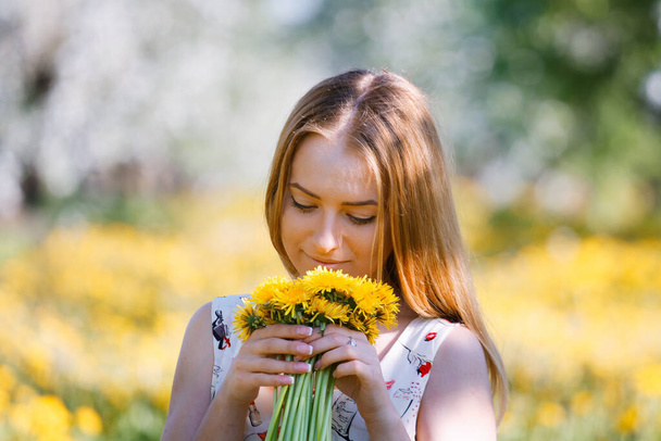 girl in a blooming garden with a bouquet of dandelions 2020 - Photo, Image