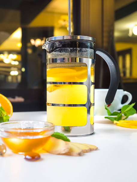 Hot tea with lemon, orange, ginger and mint on a white table in a restaurant - Fotografie, Obrázek
