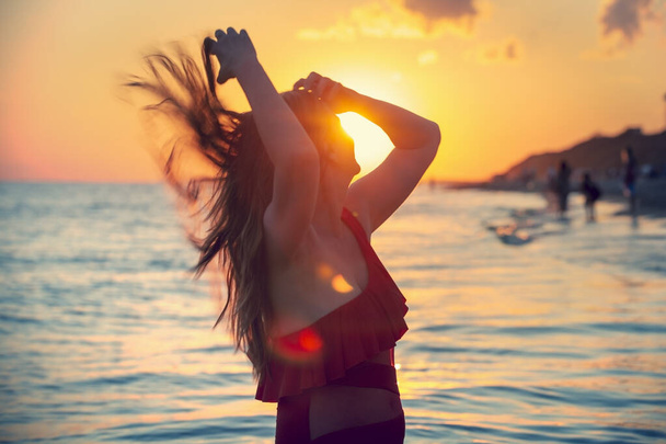 mujer despreocupada en traje de baño rojo bailando al atardecer en la playa. mujer madura relajación vitalidad estilo de vida saludable - Foto, imagen