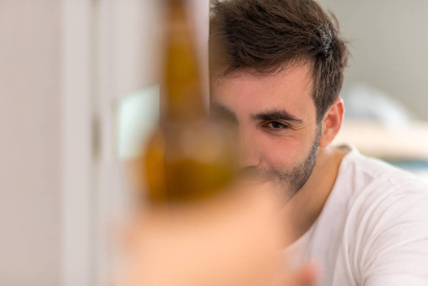 Blurred silhouette of bottle of beer and young man on the background. - Foto, afbeelding