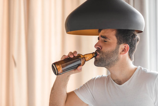Side view of young man drinking cool beer from the bottle. - Φωτογραφία, εικόνα