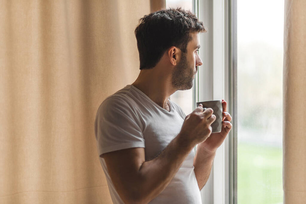 Photo of relaxed businessman with cup of coffee near window at home. - Foto, imagen