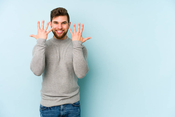 Young caucasian man isolated on blue background showing number ten with hands. - Photo, Image