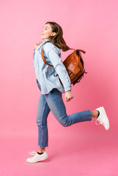Νεαρή μαθήτρια που πηγαίνει σχολείο απομονωμένη σε ροζ φόντο - Φωτογραφία, εικόνα