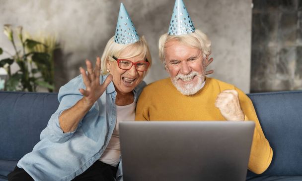 Cheerful caucasian senior couple making video call on laptop for birthday or anniversary celebration. Videoconference holiday greetings concept - Photo, Image