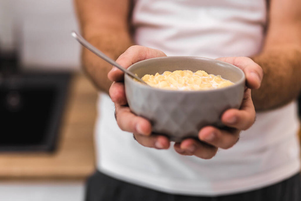 Cropped photo of man holding bowl of cereal with spoon. - Foto, Imagem