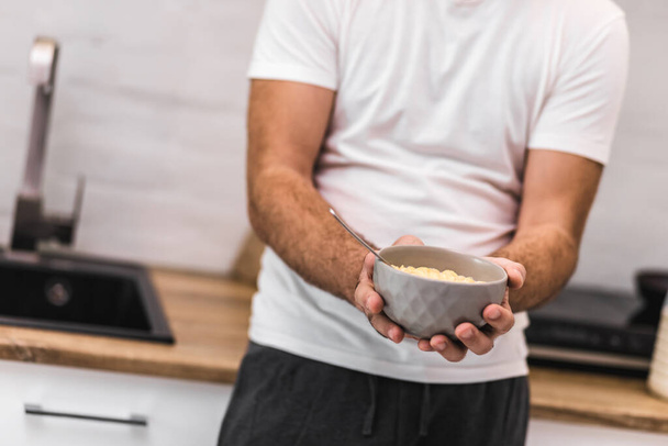 Cropped photo of man holding bowl of cereal with spoon. - Фото, зображення