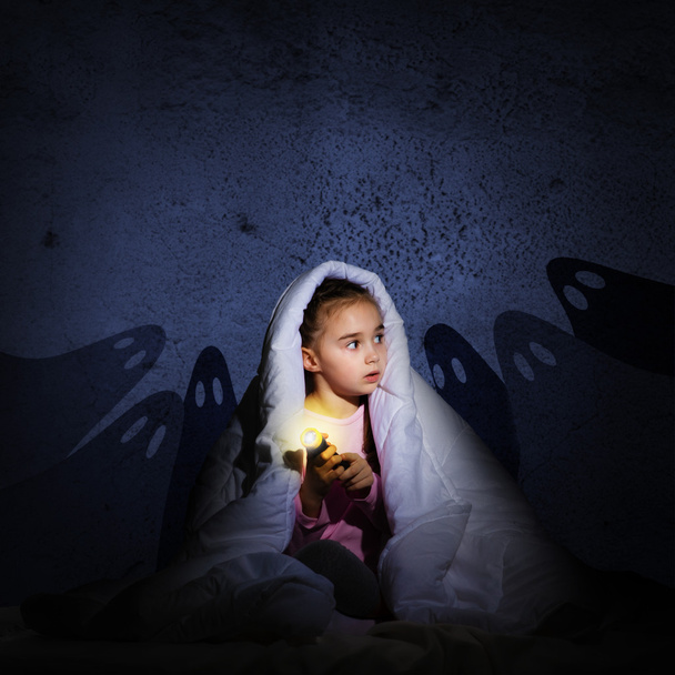 girl under the covers with a flashlight - Foto, Bild