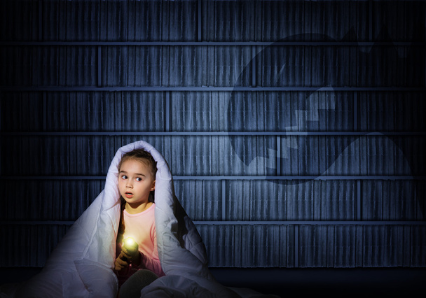 girl under the covers with a flashlight - Photo, Image