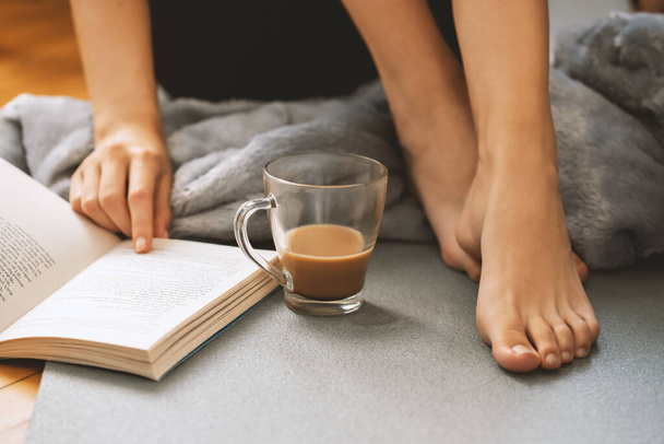 Молода дівчина читає цікаву книгу і готує свіжу чашку кави у вільний час
. - Фото, зображення