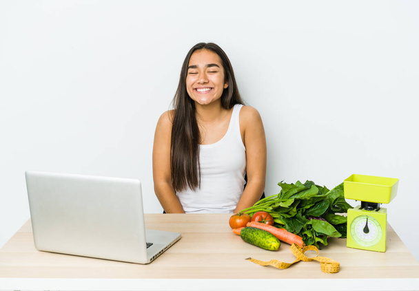 Junge Ernährungsberaterin asiatische Frau isoliert auf weißem Hintergrund lacht und schließt die Augen, fühlt sich entspannt und glücklich. - Foto, Bild
