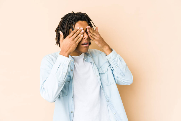 Νεαρός Αφροαμερικάνος ραστάς που φοβάται να καλύψει τα μάτια με τα χέρια. - Φωτογραφία, εικόνα