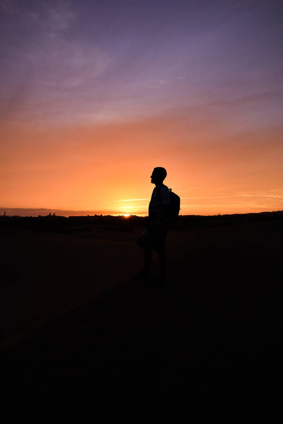 Silhouet van een man die naar de zonsondergang kijkt. - Foto, afbeelding
