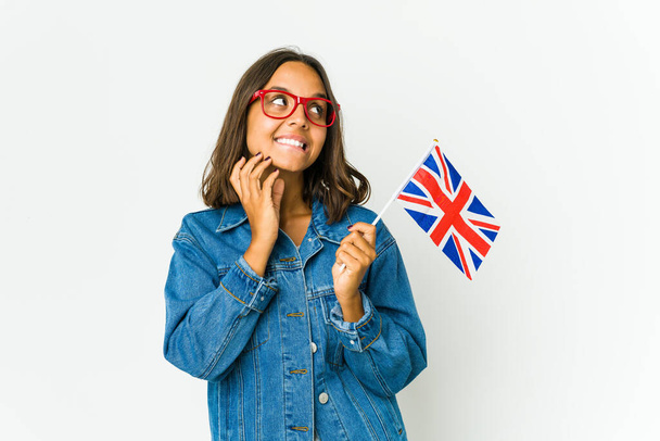Junge lateinische Frau mit einer englischen Flagge auf weißem Hintergrund, die sich einen Plan ausdenkt und eine Idee entwickelt. - Foto, Bild