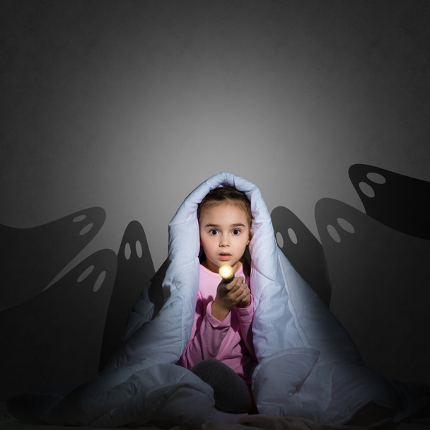 girl under the covers with a flashlight - Φωτογραφία, εικόνα