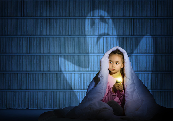 girl under the covers with a flashlight - Foto, afbeelding