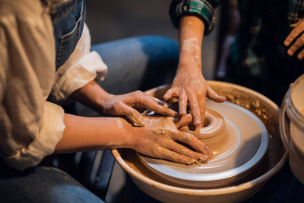 a pretty girl and a blond boy sculpt a plate on a potters wheel in an art Studio. - Fotó, kép