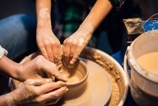 joven madre e hijo esculpir platos de barro en un taller de cerámica, primer plano. - Foto, imagen